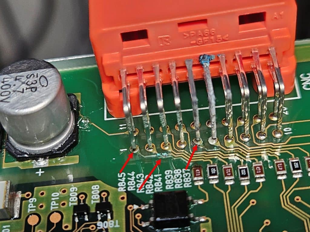 The inside of a battery control unit with corrosion caused by acid leaking into it. There are three traces with arrows pointing out them that are obviously damaged by acid.