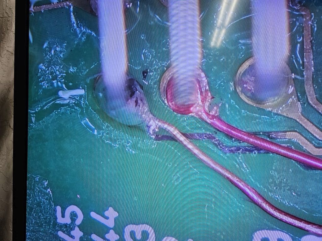 A magnified image of two pins with Magnet Wire wrapped around them one has already been soldered the other is not