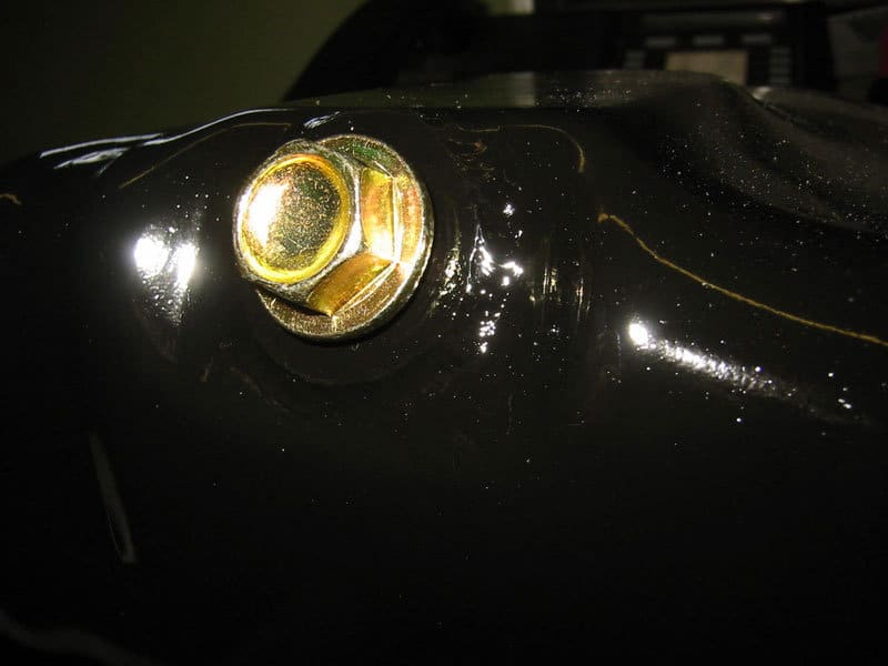Oil pan repair complete. Glossy black paint job and new drain plug installed.