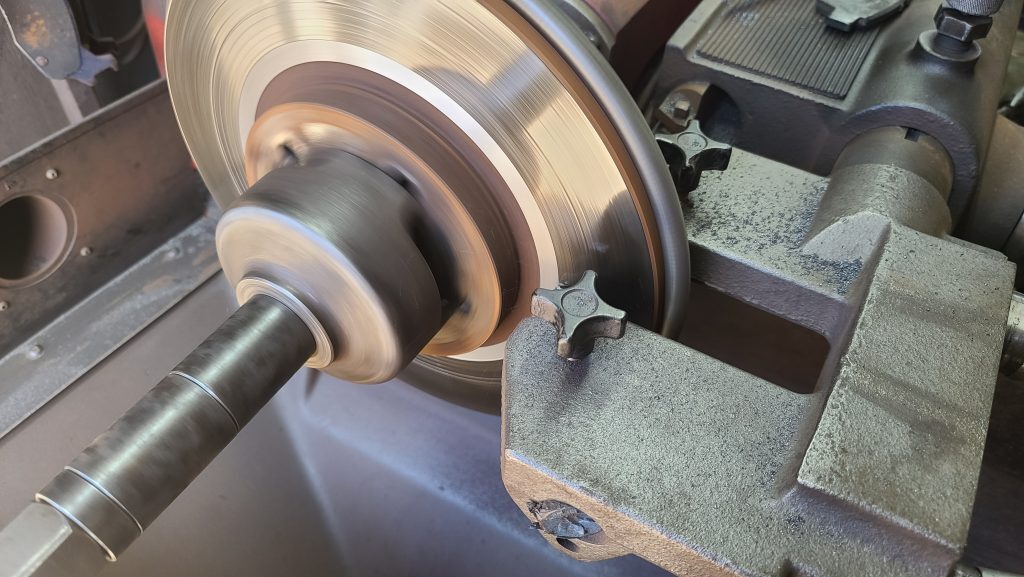 Brake rotor spinning in brake lathe with chips of metal flying off