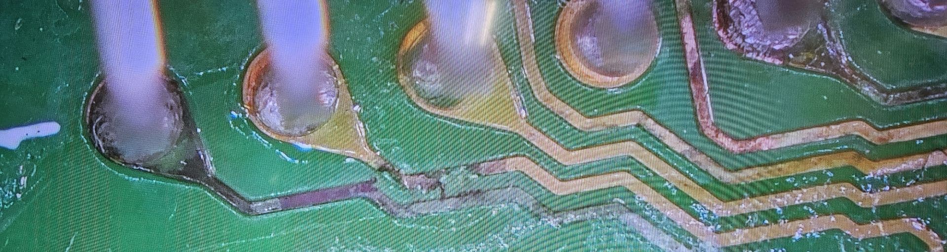 A magnified image of a circuit board with a broken Trace