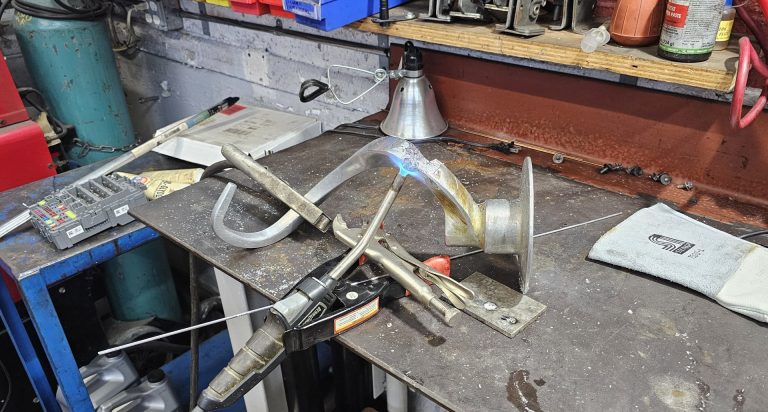 A large aluminum dough hook being pre-heated with a torch for welding