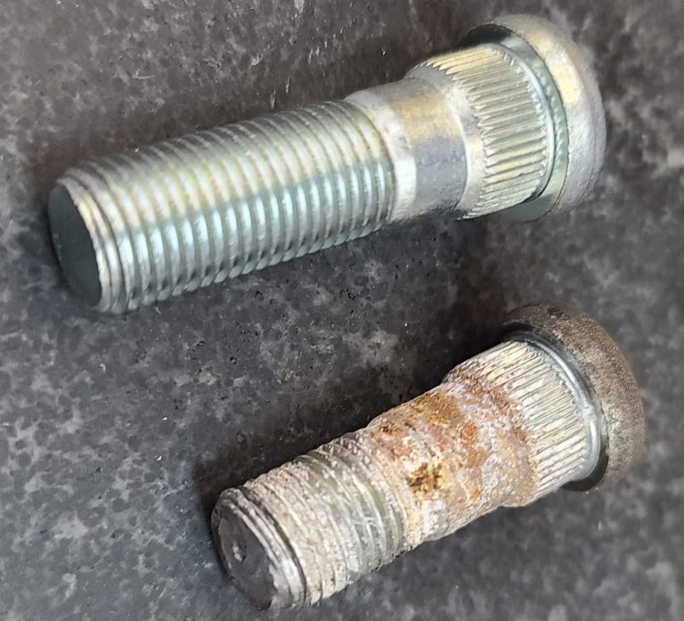 Broken Subaru lug stud sitting next to a new stud