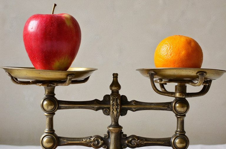 An apple and an orange on a scale.