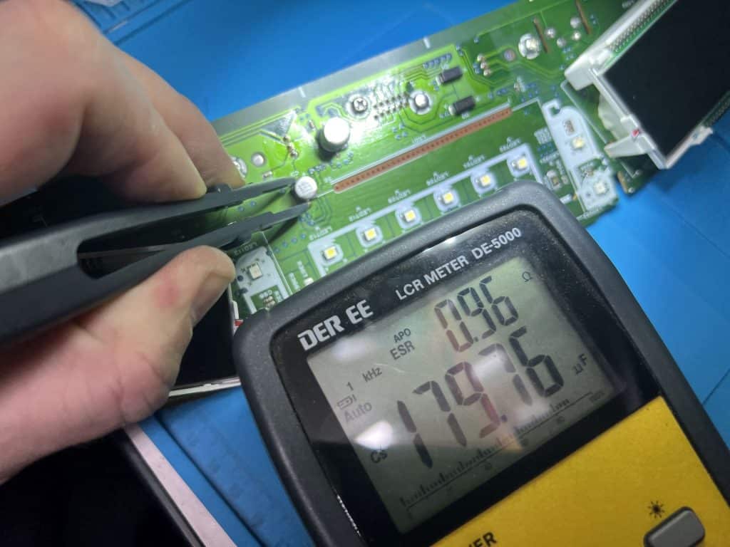 Testing a capacitor on a Honda Civic speedometer circuit board with an LCR meter.