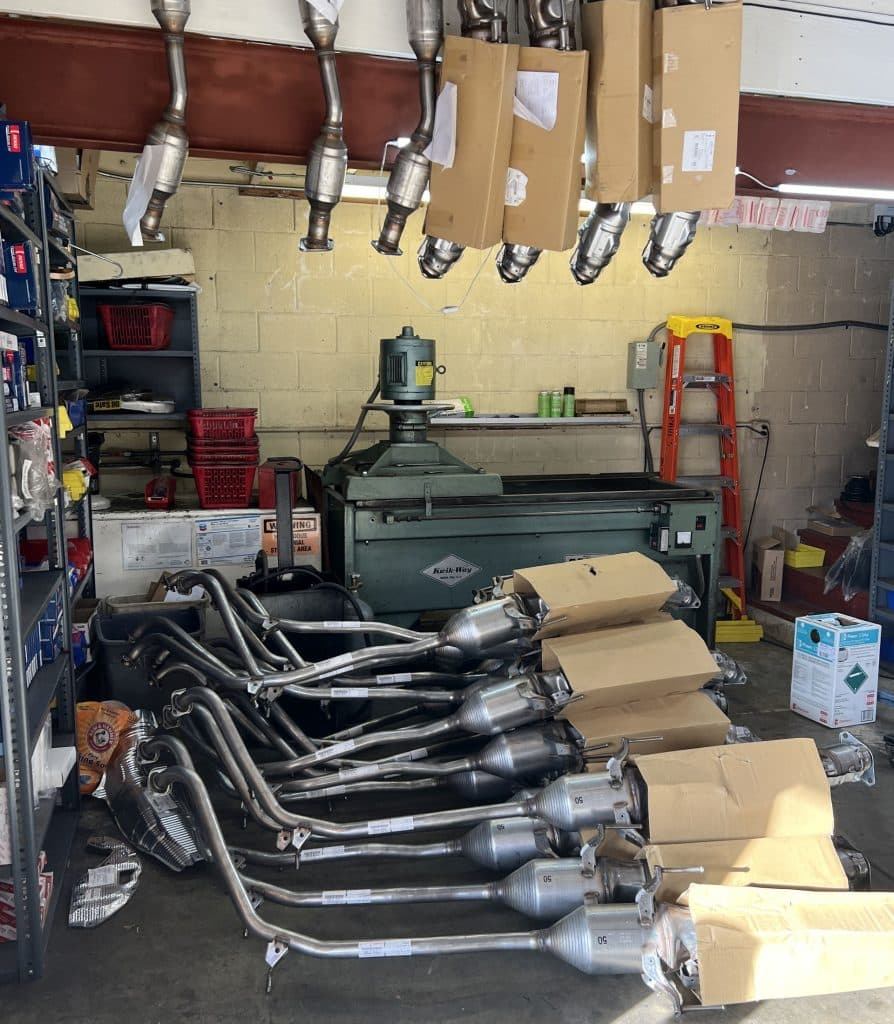 25 catalytic converters laying on the floor and 7 hanging on the wall.