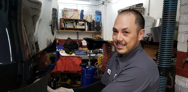 An image of a smiling mechanic working on a car.