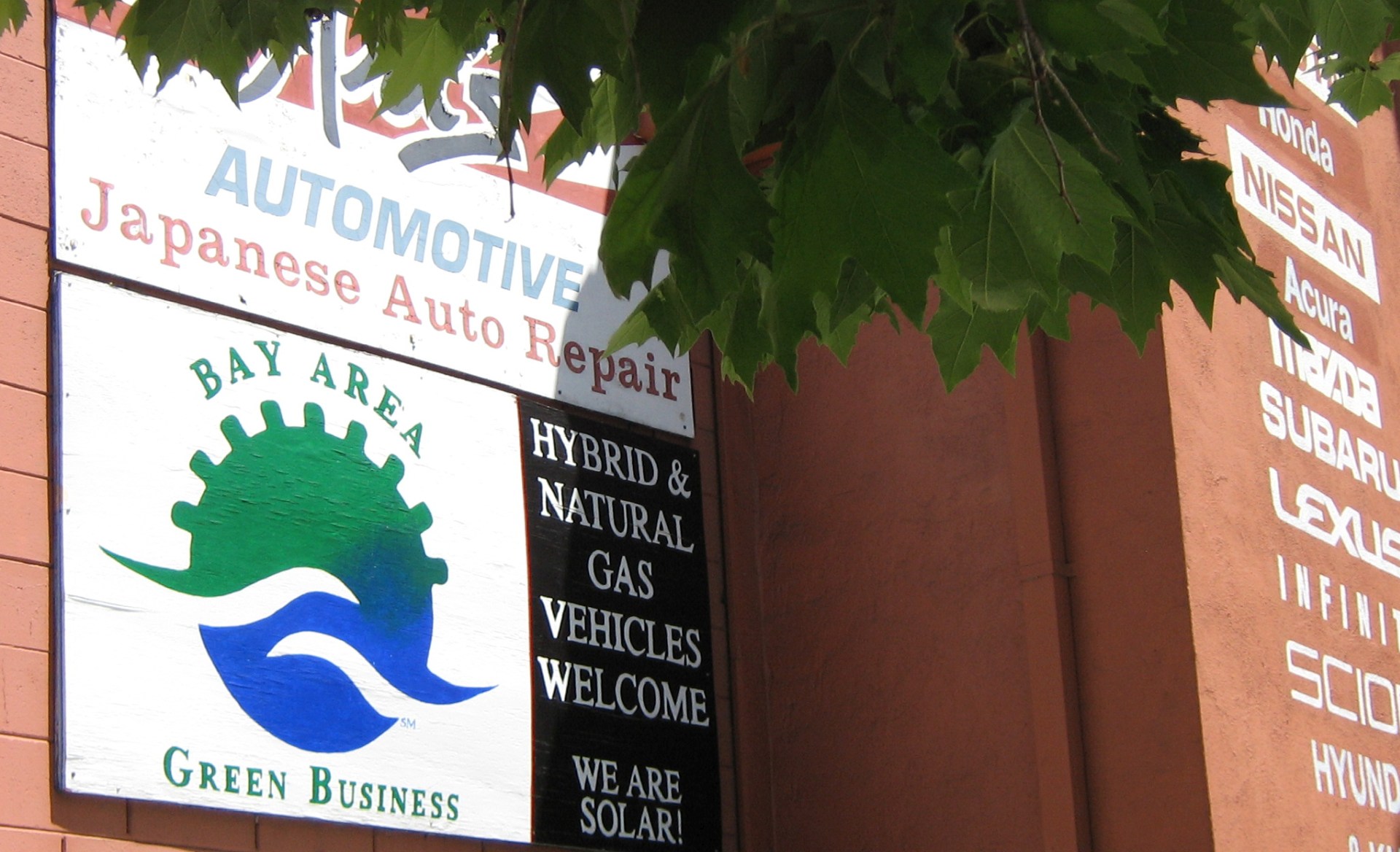 A picture of a Bay Area Green Business sign on the outside of an auto repair shop.