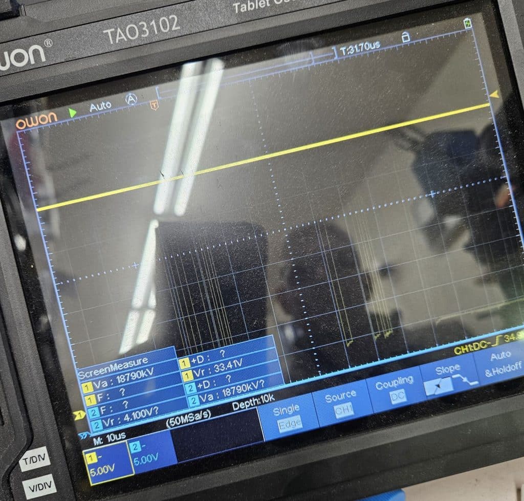 A picture of a portable oscilloscope screen displaying an irregular waveform.