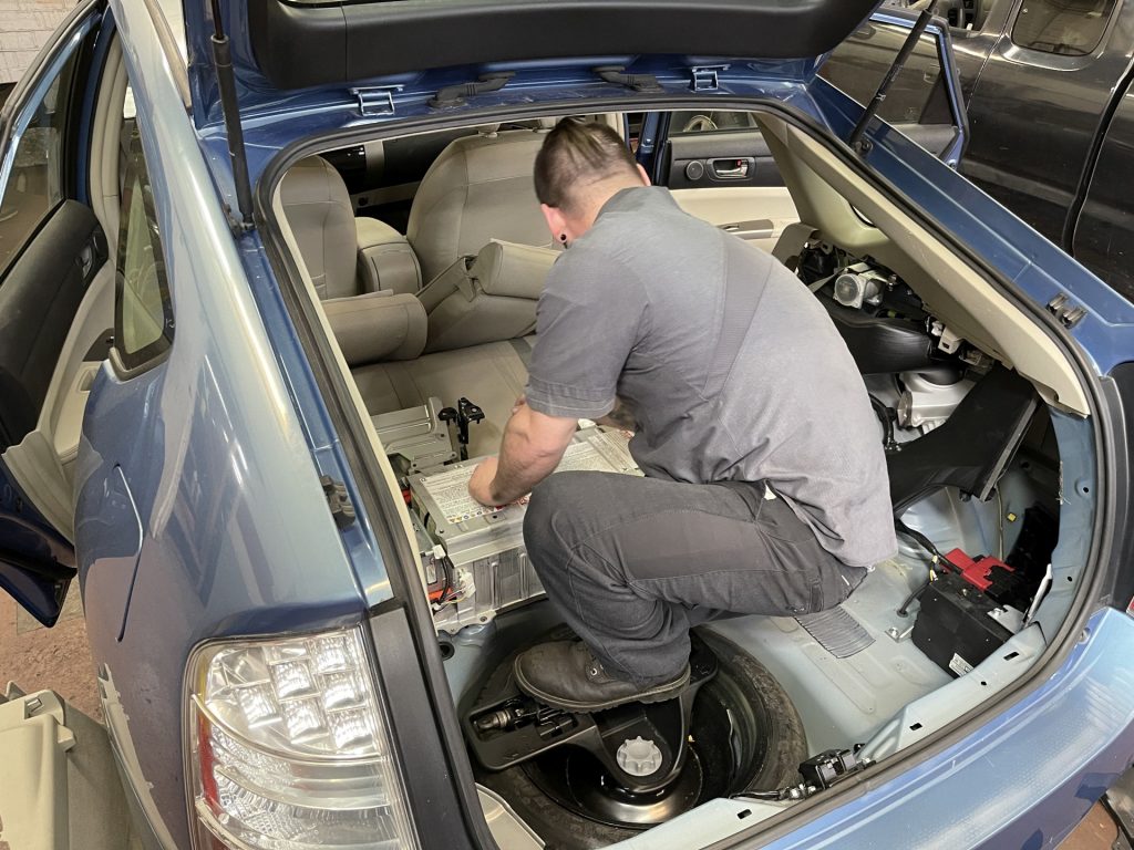 A technician replacing a hybrid battery in a Toyota Prius.