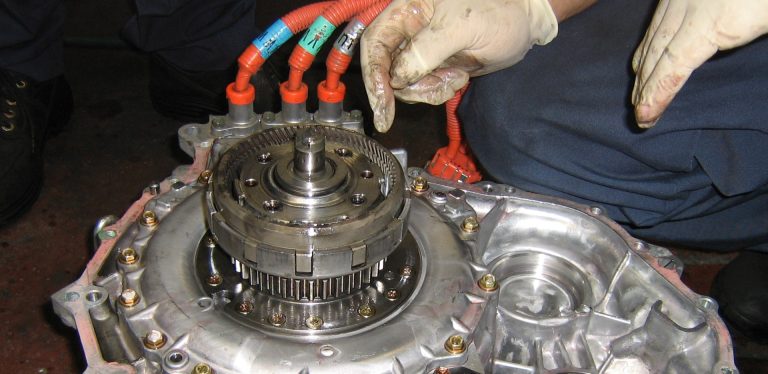 A mechanic repairing a disassembled hybrid transmission