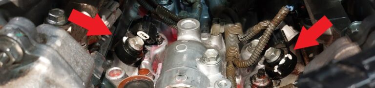 Two installed knock sensors with arrows identifying them