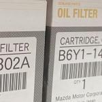 Genuine Mazda oil filters stacked on a shelf.