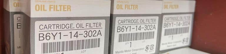 Genuine Mazda oil filters stacked on a shelf.