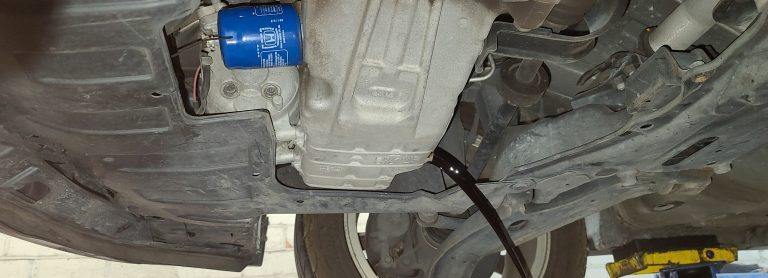 the underside of a car with motor oil draining from the oil pan.