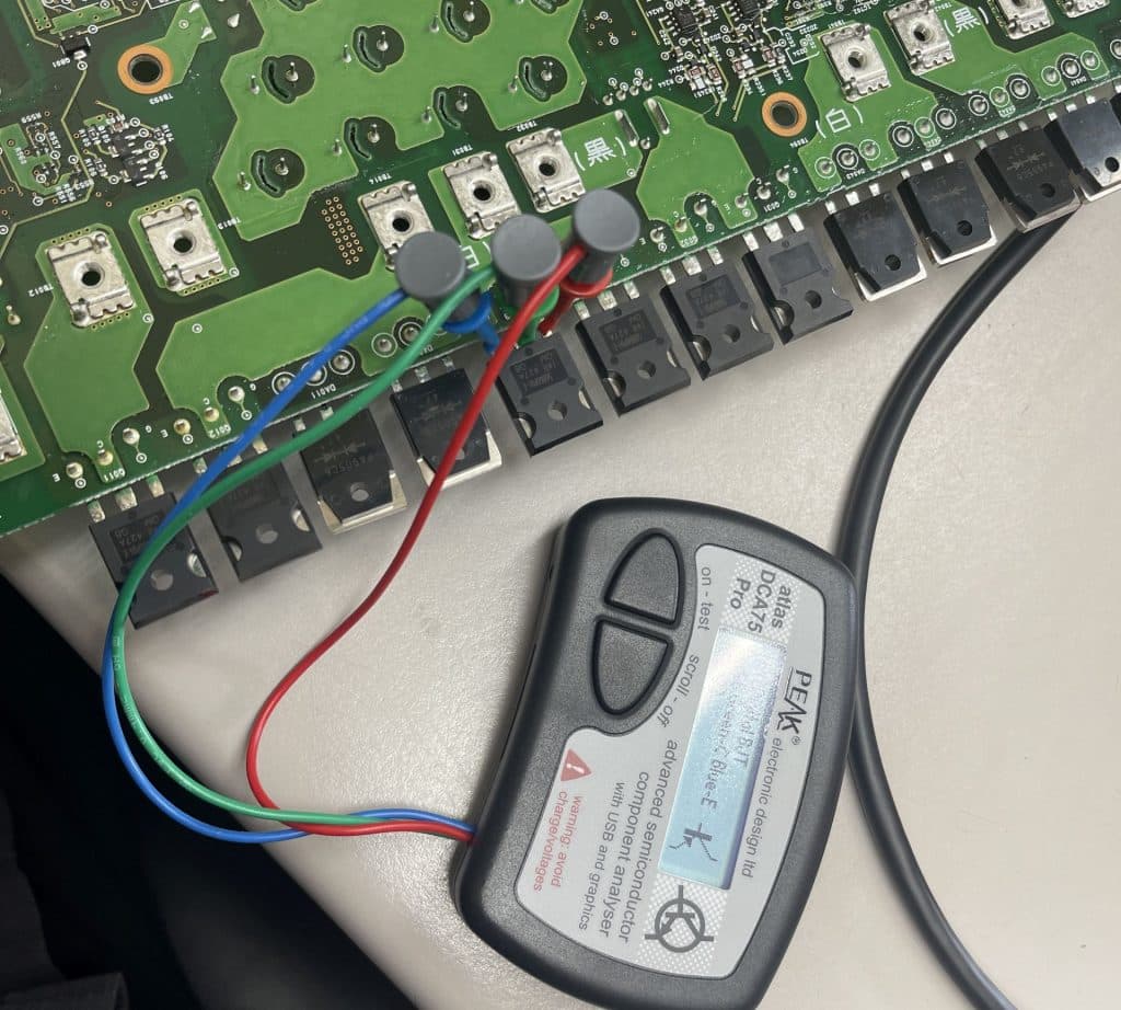 Image of testing a plug-in Prius hybrid on-board charger circuit board with a Peak component tester prior to repair.
