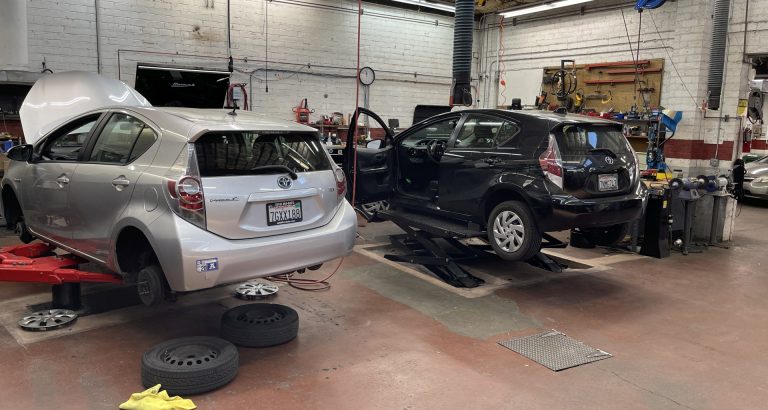 Two Prius cars on racks being serviced