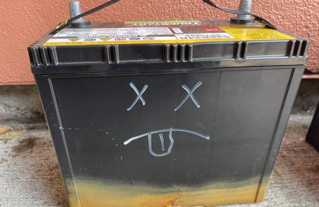 A picture of a "dead" Prius battery with a face drawn on it. X's for eyes, frown, and tongue sticking out.