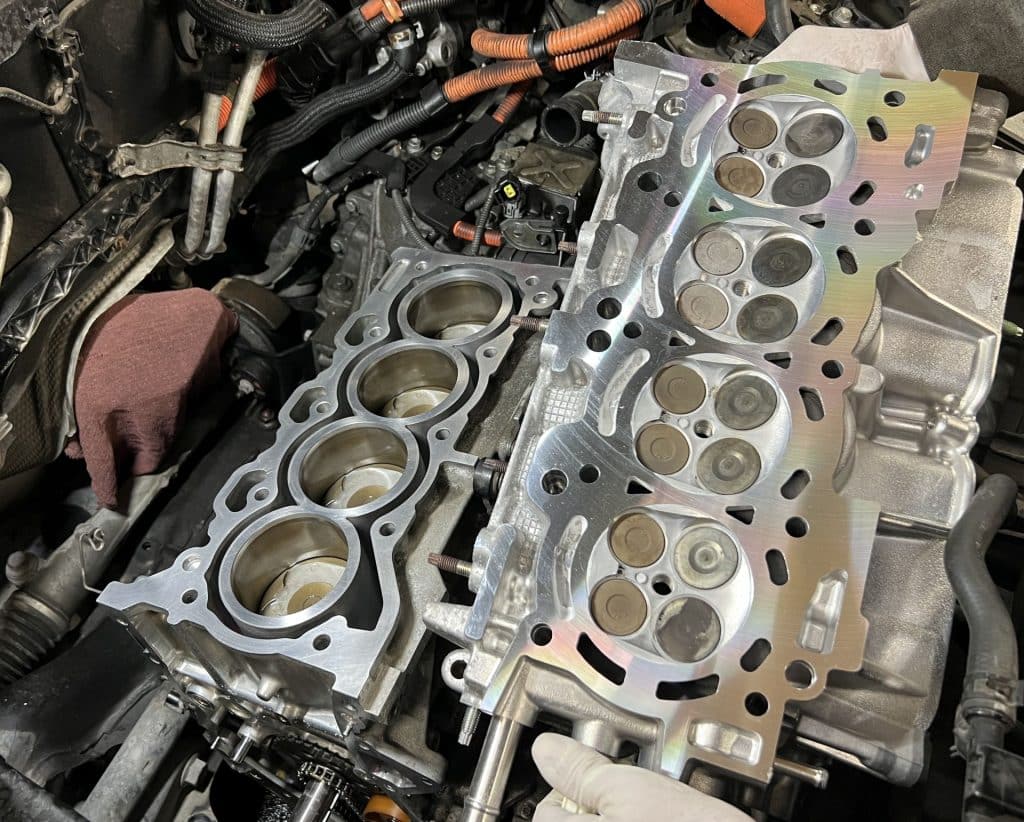 Shiny freshly machined Prius cylinder head held next to a cleaned engine block.