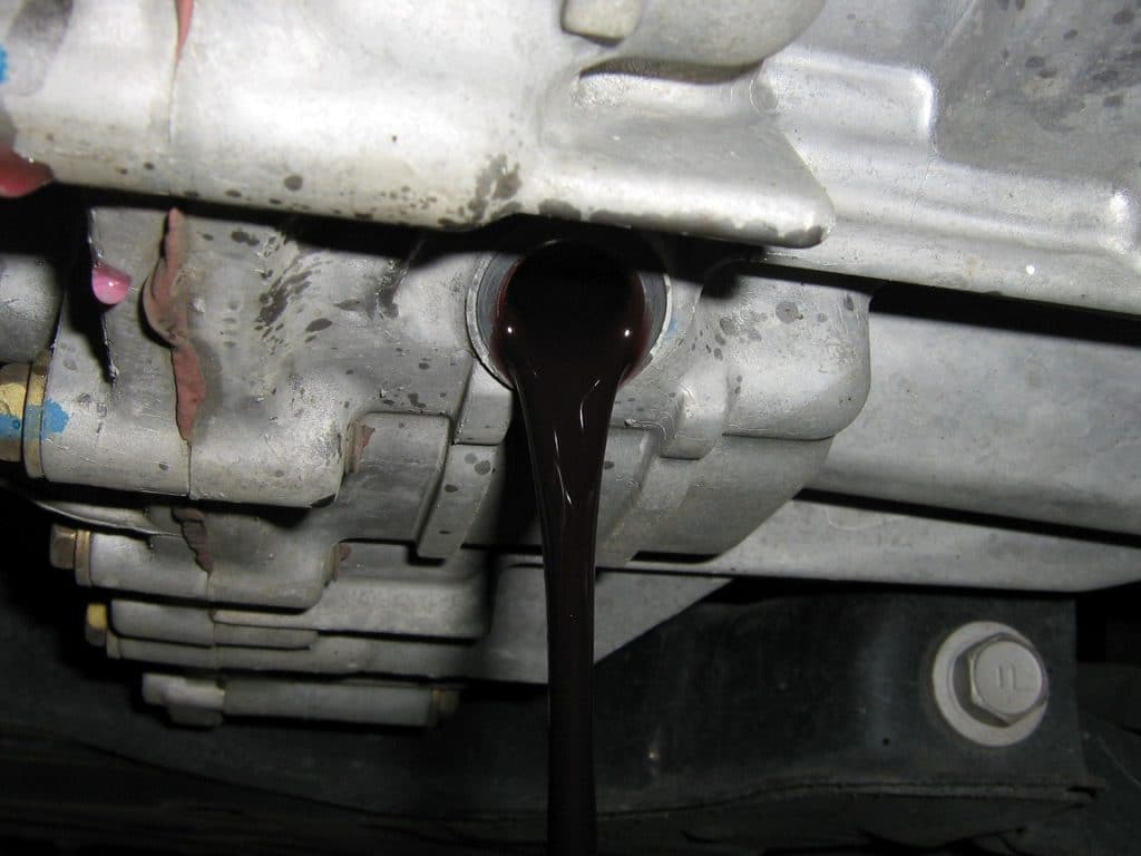 Dark transmission fluid pouring from a hybrid transmission during a fluid service.