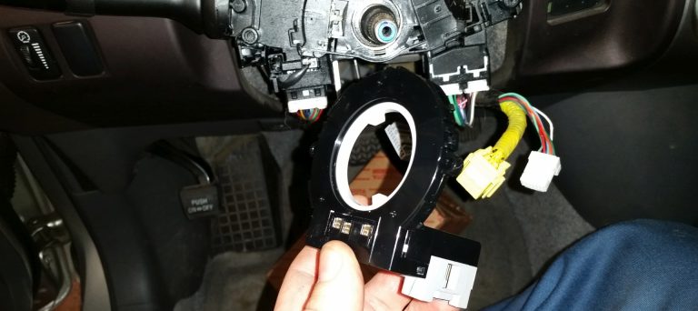 A mechanic replacing a steering angle sensor on a Toyota.