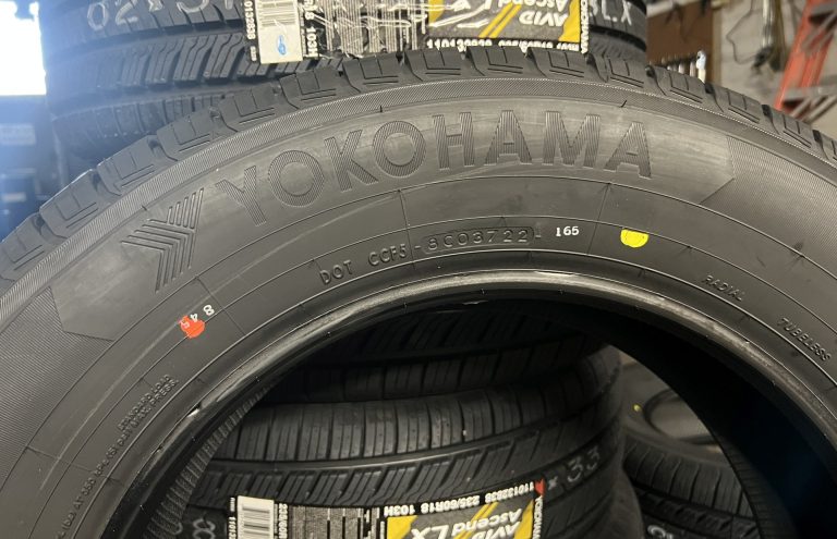 A new tire sitting in front of a stack of tires