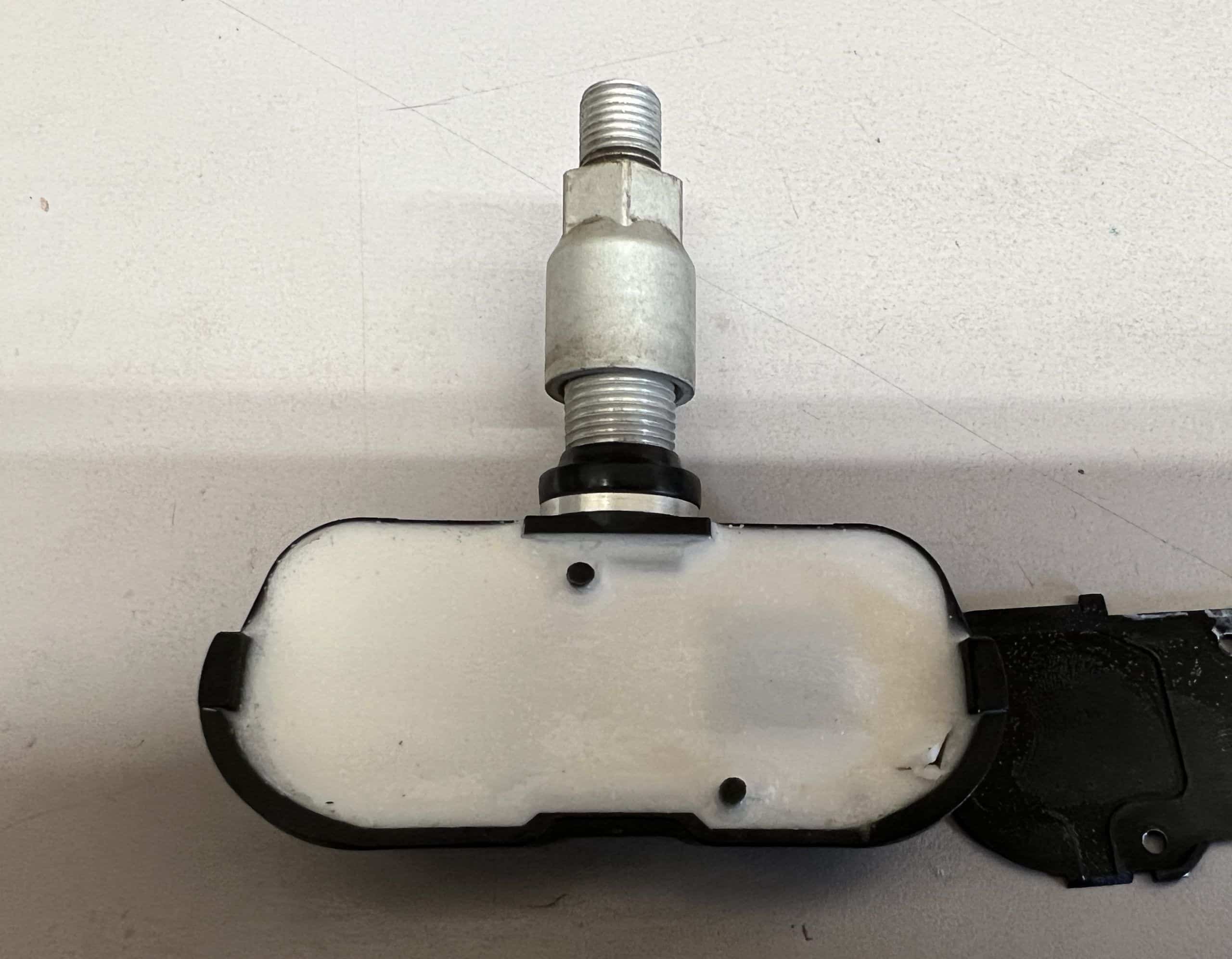 The back side of a TPMS sensor with potting compound covering the TPMS sensor battery.